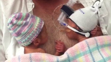 Cute Twins Holding Hands on Their Father’s Chest